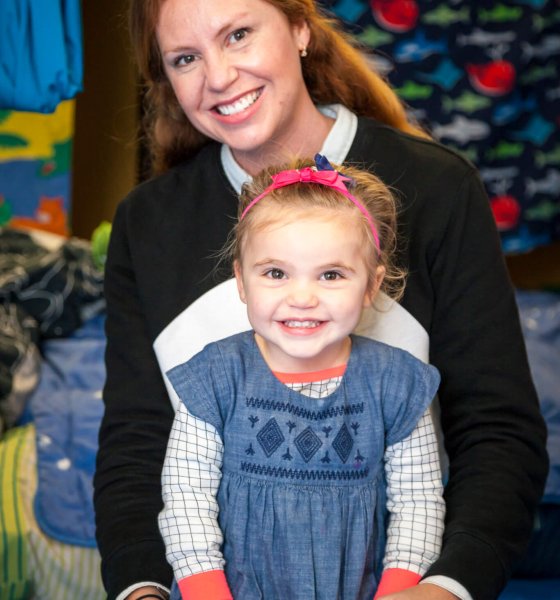A parent holding her smiling toddler during a behaviour support session