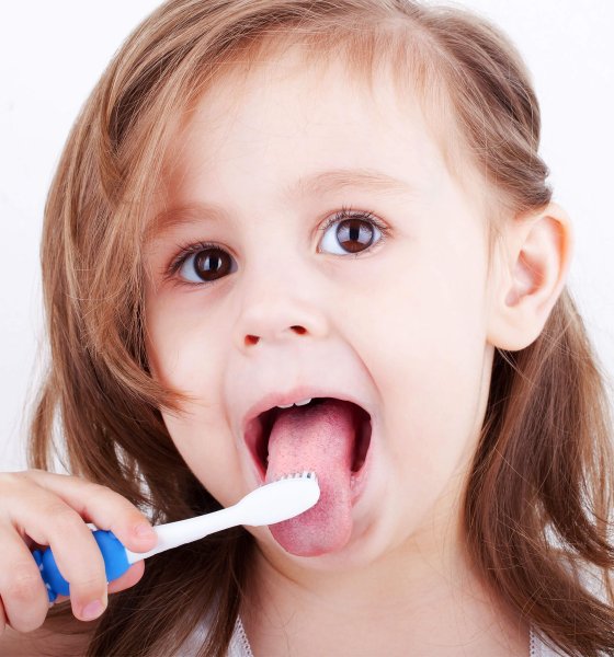 A young child with their mouth open and tongue out during oral function therapy