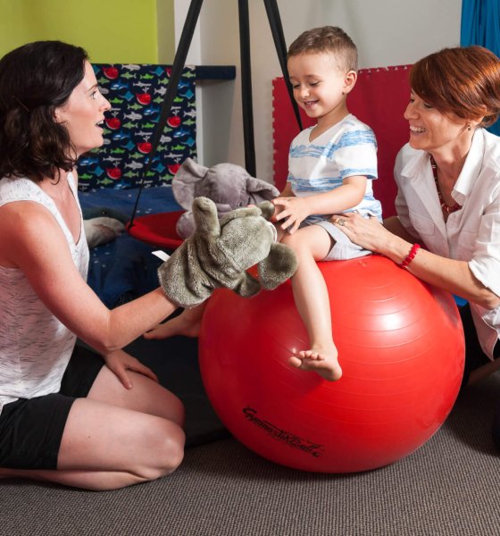 A young child and parent engaging with puppets during speech and language therapy