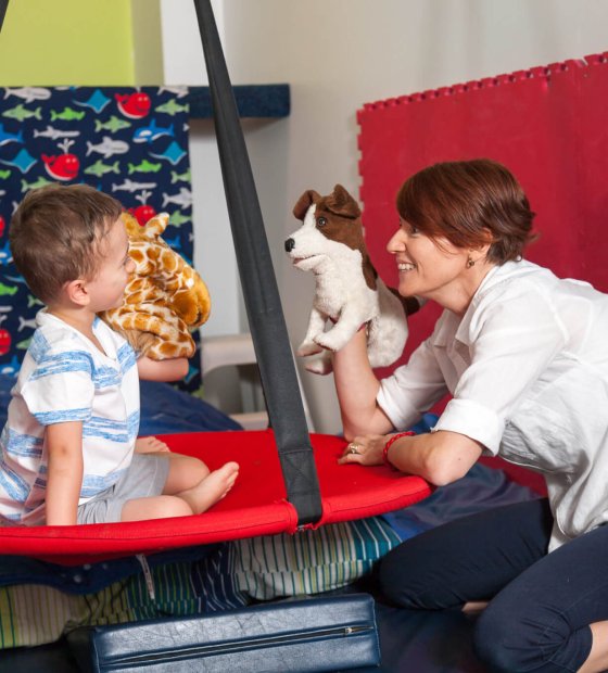 Leana and a child playing with puppets during developmental therapy